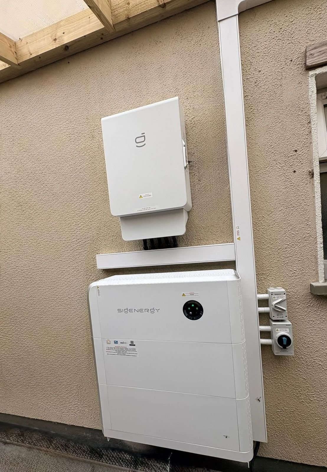 Sigenergy inverter mounted above a battery unit on an exterior wall, by Elececo Engineering